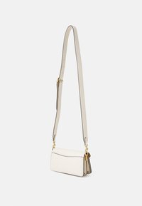 Vit läder crossbody-väska med texturerad finish, guldfärgad hårdvara, justerbar rem och kontrasterande detaljer. Kompakt design med klaffstängning.