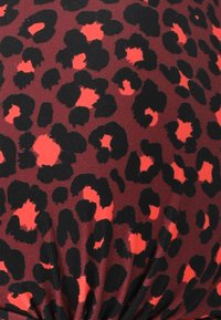Tessuto con stampa leopardata in nero e rosso su uno sfondo color maroon, caratterizzato da una trama liscia con dettagli arricciati nella parte inferiore.
