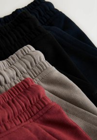 Pantalones joggers de algodón en negro, azul marino, gris claro y burdeos, con cinturillas elásticas y tela texturizada. Corte de ajuste relajado.