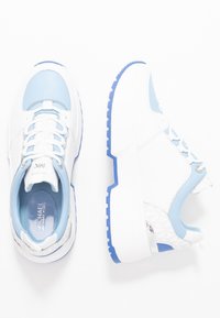 Vita sneakers med ljusblå detaljer, med en strukturerad ovandel och en kraftig vit sula med blå utsmyckningar och snörningsdesign.