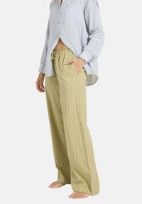 Chemise à rayures bleu clair à boutons associée à un pantalon large à rayures vert olive avec une taille élastique et des poches latérales.