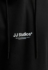 Schwarzer Hoodie aus weichem Stoff mit Kapuze und Kordelzug. Vorn befindet sich ein Logo in weißem Text, darunter ist zusätzlicher Text in kleinerer Schrift.