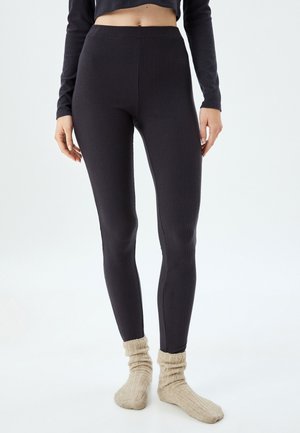 Geribbelde, hoog getailleerde leggings in donkergrijs, gemaakt van zacht stof. Gecombineerd met lichtbeige, gestructureerde sokken.