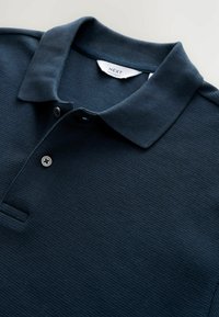 Marineblå polo skjorte lavet af struktureret stof, med klassisk krave og tre-knaps lukning. Mærkeetiket synlig inden i kraven.