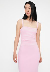 Φόρεμα εφαρμοστό, χωρίς μανίκια, από απαλό ροζ ύφασμα; τετράγωνη λαιμόκοψη και ομαλή υφή; λεπτή σιλουέτα με μακρύ κόψιμο.