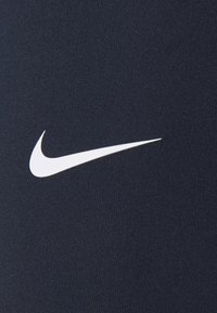 Tejido atlético de color navy con una textura suave. Presenta un destacado logo de Nike en color blanco en el lado izquierdo.