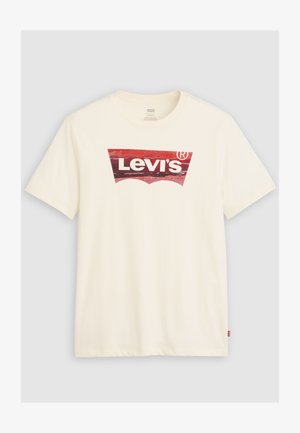 Vit t-shirt med korta ärmar, med en sliten röd Levi's-logotyp i mitten och en liten röd Levi's-etikett i sidans söm.