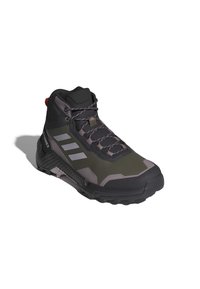 Scarpe da trekking verde scuro e grigio con design a caviglia alta, superfici testurizzate, tre strisce bianche sul lato e suola nera robusta.