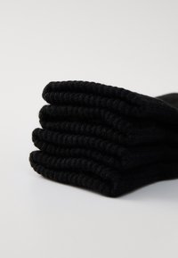 Black cotton socks stacked neatly, featuring ribbed texture and soft fabric, designed for comfort and durability.