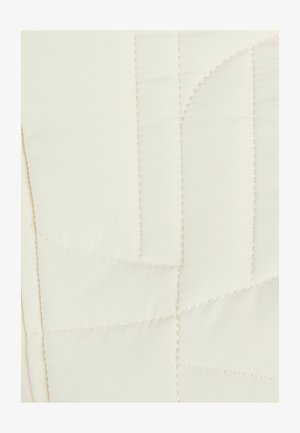 Gequilte beddengoed in crèmekleurige stof met zichtbare stiksels, met geometrische vormen en een gladde textuur.