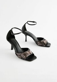 Sandales à talons hauts noires avec un design à bout carré, dotées d'une sangle en sequins dans des tons de rose et de marron, et d'une sangle autour de la cheville avec une boucle.
