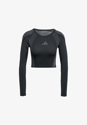 Black long-sleeve crop top made from stretch fabric features a fitted design, textured patterns, and a logo on the chest. Striped accents on sleeves.