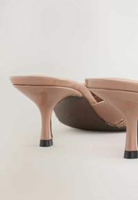 Beige lakované kožené vyšší mule s lesklým povrchem, otevřenou špičkou a úzkými jehlovými podpatky s černým akcentem.