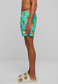 Shorts de bain avec un fond aquatique, ornés d'ananas orange et de motifs géométriques. Dotés d'une taille élastique et d'un cordon de serrage.