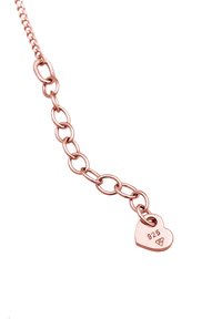 Bracciale in oro rosa con maglie intrecciate, dotato di un ciondolo a forma di cuore contrassegnato "925" per autenticità in argento sterling.