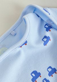 Hellblauer Baumwollstoff mit einem wiederholten Muster von kleinen blauen Lastwagen mit orangen Rädern. Rundhalsausschnitt mit weicher Textur.