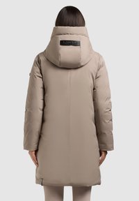 Béžový nadýchaný kabát s veľkou kapucňou, na chrbte s logom. Hladká, prešívaná textúra so štíhlym strihom a bočnými vreckami.