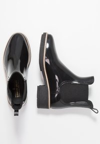 Bottes de pluie noires vernies à chevilles avec des panneaux latéraux élastiques, semelles détaillées en beige et talons carrés, présentées en vues de dessus et de côté.