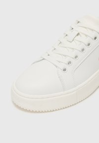 Sneaker bianco in pelle liscia con punta rotonda, suola in gomma testurizzata e lacci piatti. Presenta audaci accenti laterali e dettagli perforati.