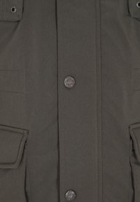 Donkergroen stoffen jack voorzijde met klepzakken en metalen knopen met de gravure "Dreimaster Nordisch MMX."