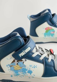 Modré a biele vysoké tenisky s tématikou Pokémon majú textúrovaný dizajn, grafiku postáv a suchý zips so znakem.