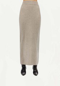 Ribbad grå midi kjol med hög midja, slät textur och en figurnära silhuett, kombinerad med svarta ankelstövlar.