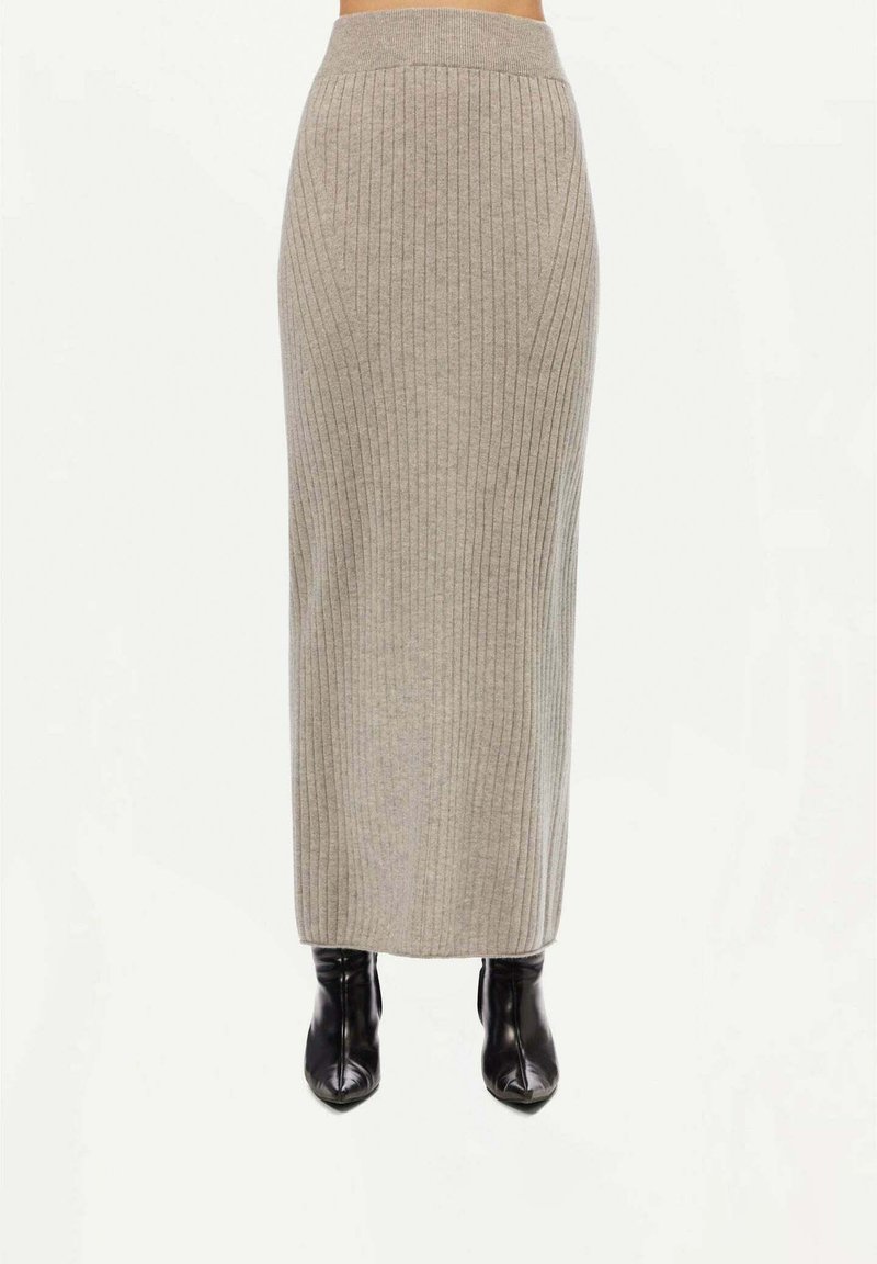 Ribbad grå midi kjol med hög midja, slät textur och en figurnära silhuett, kombinerad med svarta ankelstövlar.