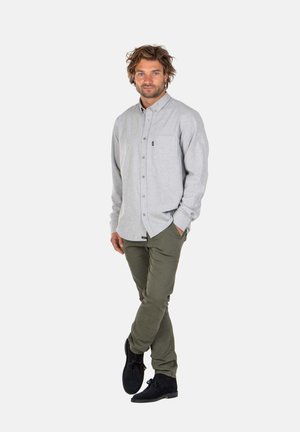 Hellgrau knopfbares Hemd mit langen Ärmeln und einer Brusttasche, kombiniert mit olivgrünen Hosen und schwarzen Schuhen. Glatte Textur.