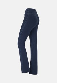 Leggings de mezclilla azul oscuro con una textura suave, silueta ajustada y una cintura más alta. Presentan detalles de costura sutil a lo largo de los lados.