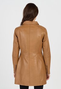 Helle Lederoverjacke mit taillierter Silhouette, langen Ärmeln und einem Kragen. Verfügt über Reißverschluss-Taschen und vertikale Nahtdetails.