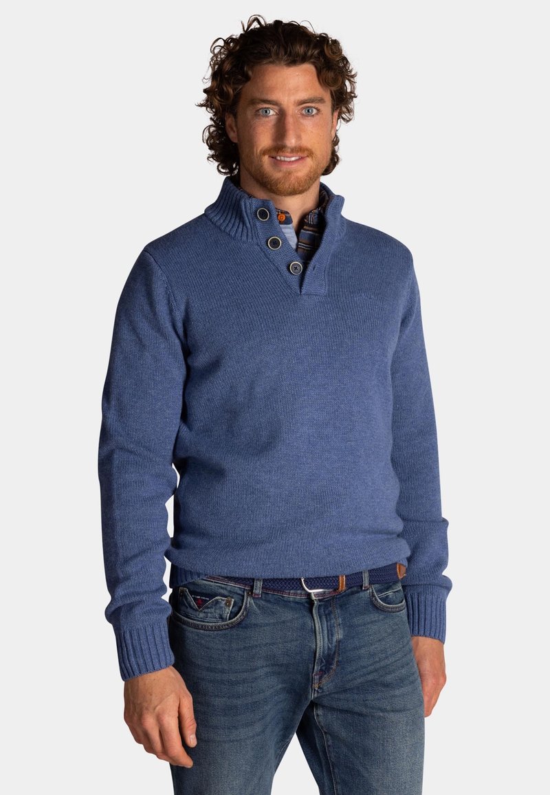 Blauwe gebreide trui met een hoge kraag, voorzien van drie grote knopen. Draagt over een geruit shirt, met geribbelde manchetten en zoom.