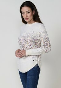 Pulover crem cu pete multicolore, mâneci lungi și un tiv curbat. Prezintă o textură netedă și detalii subtile.