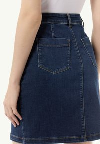 Dunkelblaue Jeansrock mit tailliertem Schnitt, hohem Bund und zwei Gesäßtaschen. Mit sichtbaren Nähten und geradem Saum.