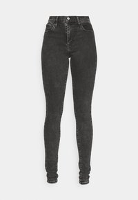 Jeans ajustados de tiro alto en negro, hechos de denim, con cinco bolsillos, cierre de botón y cremallera, con una textura suave y ligeramente desgastada.