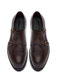 Een paar gepolijste donkerbruine leren double monk strap dresschoenen, van bovenaf bekeken, op een witte achtergrond.