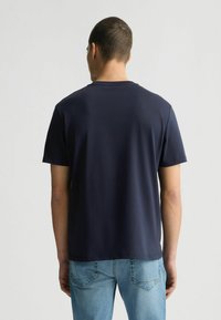 T-shirt in cotone blu navy con maniche corte, collo rotondo e vestibilità rilassata. La schiena presenta un design minimale senza motivi o loghi visibili.