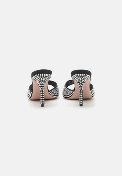 High-heeled black sandals with jeweled embellishments, open back design, and a nude insole, featuring a sleek stiletto heel.