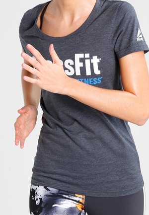 Graues Fitness-T-Shirt mit "CrossFit"-Logo in Weiß und Blau, kurze Ärmel, kombiniert mit gemusterten Leggings mit Farbspritzern.
