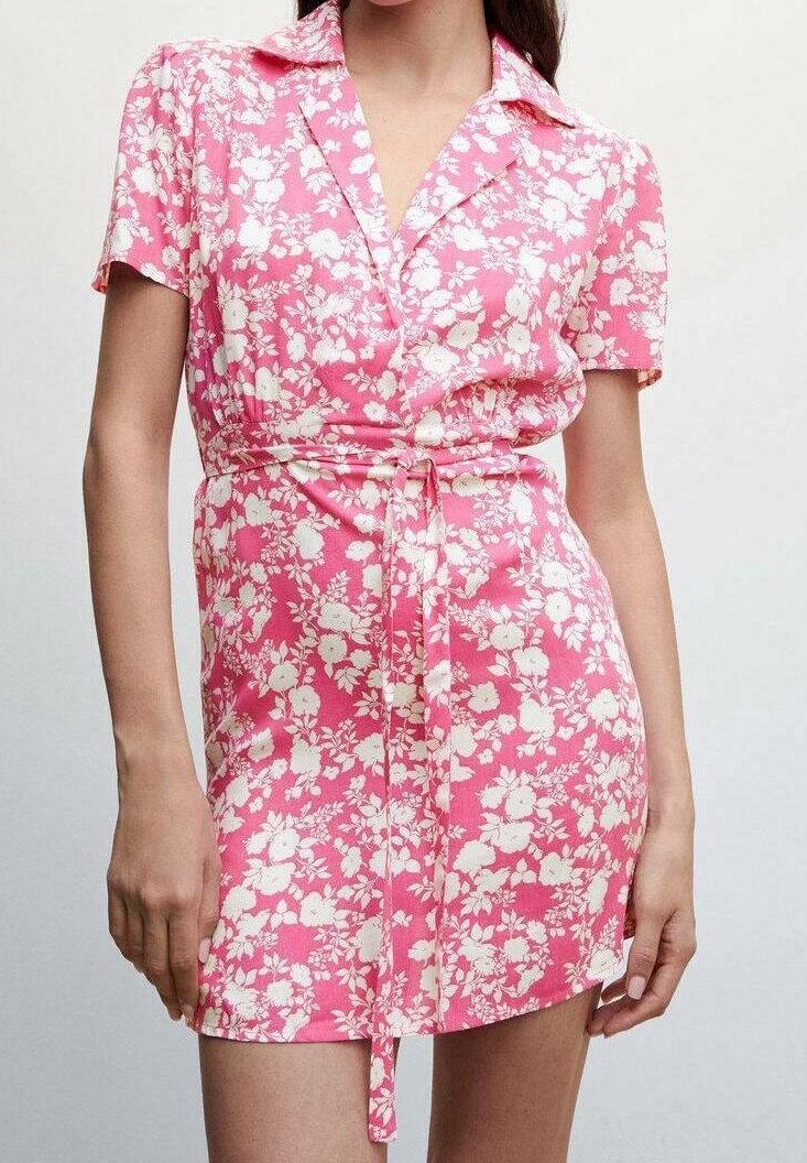 Vestido floral rosa con mangas cortas, cuello, diseño envolvente y cintura ceñida con cinturón. Presenta un patrón floral blanco en toda la prenda. Textura de tela suave.