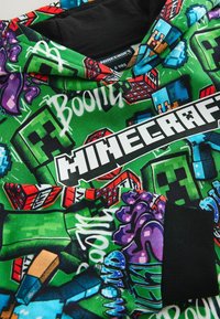 Bluza z kolorowymi grafikami Minecraft, w tym postaciami Creepera, pikselowymi narzędziami i wyrazistym napisem "Minecraft" na zielonym tle.