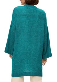 Türkisfarbener, übergroßer Strickpullover mit hohem Kragen, weiten Ärmeln und gerippten Bündchen, aus einem lockeren, strukturierten Stoff.