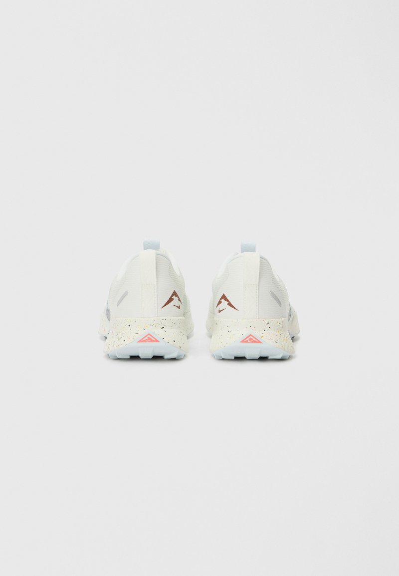 Zapatillas de running blancas con un upper texturizado, acentos en azul claro y una suela moteada que presenta un detalle triangular rojo en el talón.