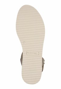 TOMS sandaler med en beige gummisula som har horisontella spår, ljusbruna remmar och en präglad logotyp nära hälen.