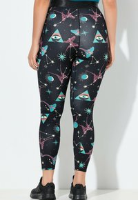 Zwarte leggings met een hemels patroon van ogen, sterren en geometrische vormen in turquoise, roze en wit. Rekbare stof, aansluitend ontwerp.