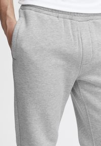 Gray sweatpants made from soft fabric with side pockets, elastic waistband, and a relaxed fit. Features a smooth texture and simple design.