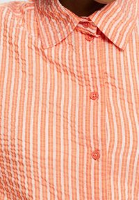 Kurzarmhemd in hellorange mit vertikalen weißen Streifen, einem geknöpften Kragen und passenden Knöpfen aus strukturierter Stoff.