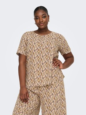 Mujer de piel oscura y cabello recogido lleva un conjunto a juego con top de manga corta beige con estampado marrón y pantalones de pierna ancha, posando con la mano en la cadera.