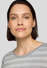 Grauer gestreifter Oberteil mit rundem Ausschnitt und strukturiertem Stoff. Das Model hat glattes dunkles Haar und einen neutralen Hintergrund.