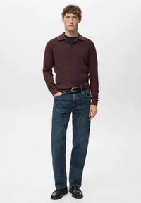 Bordowy prążkowany sweter z kołnierzem, zestawiony z ciemnoniebieskimi jeansami o prostych nogawkach oraz czarnymi skórzanymi butami. Prosty, casualowy design.