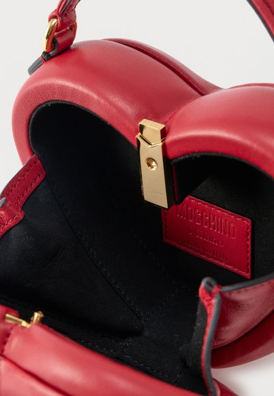 Intérieur d'un sac à main Moschino en cuir rouge avec doublure noire, fermoir doré et étiquette de marque rouge cousue indiquant "Moschino Milano Made in Italy."
